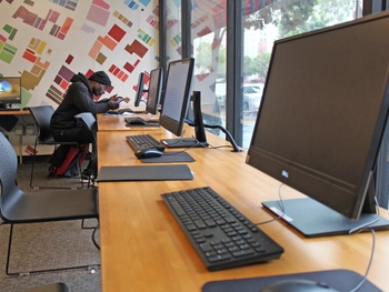 Man sits at end of desk with computers.