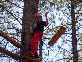 Child smiling on a ropes course.