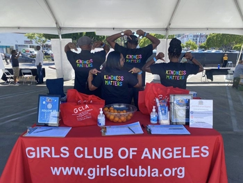 Team of staff members at a tabling event showing the "Kindness Matters" message on the back of their shirts.
