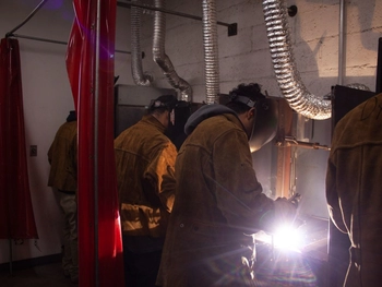Students practicing their welding skills in a workshop.