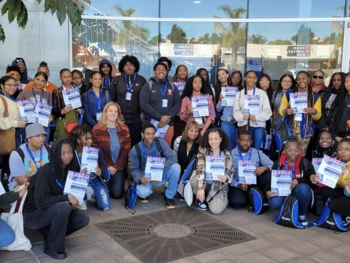 A group of participants taking a group picture holding up flyers.
